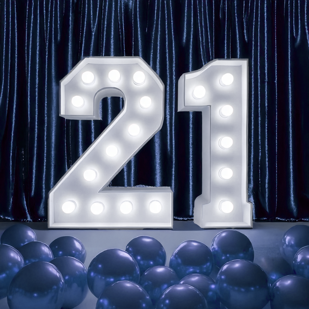 marquee lights that read "21" in front of blue velvet curtains with blue balloons scattered on the floor
