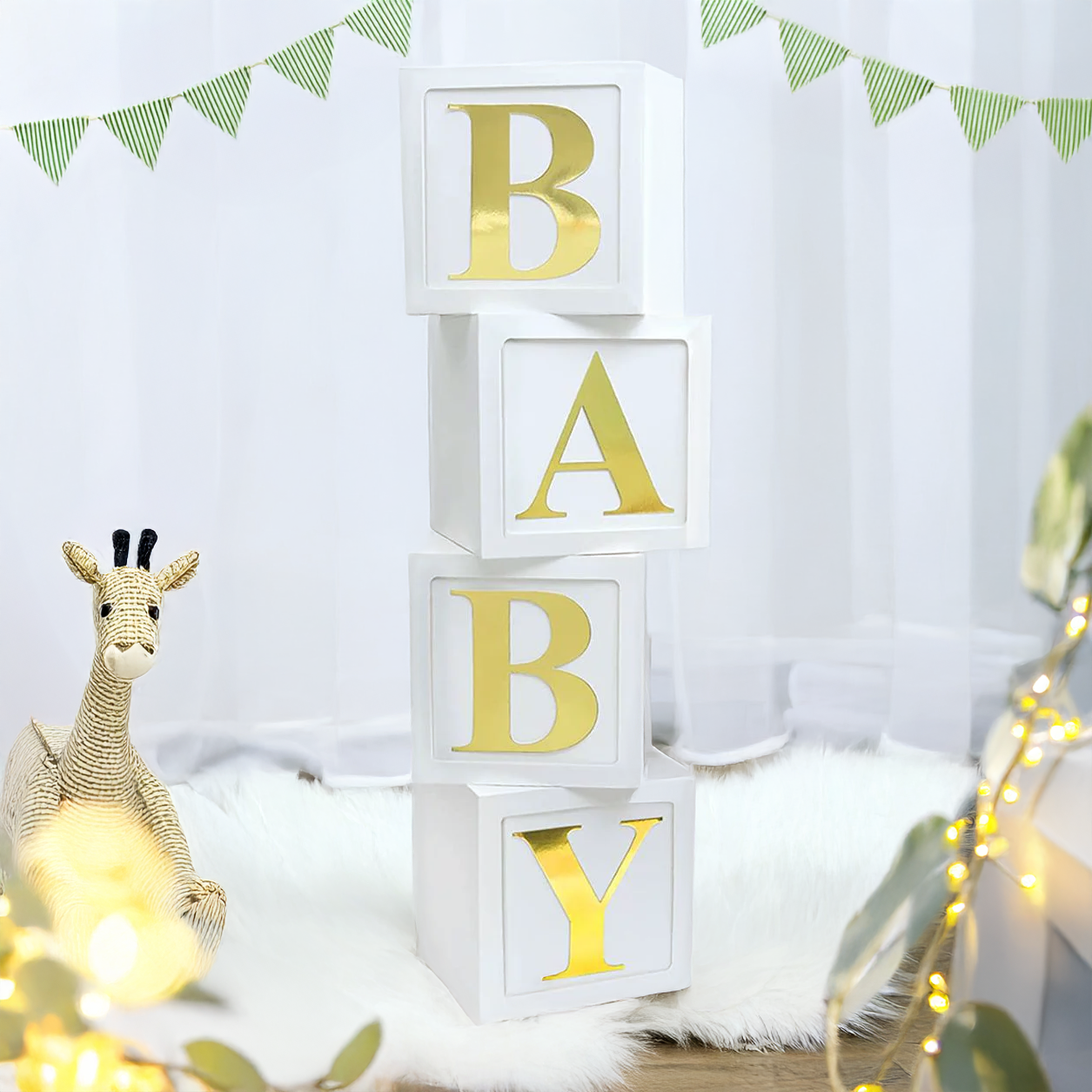 Stacked acrylic boxes spelling out 'BABY' with white base and gold lettering, displayed at a celebration event