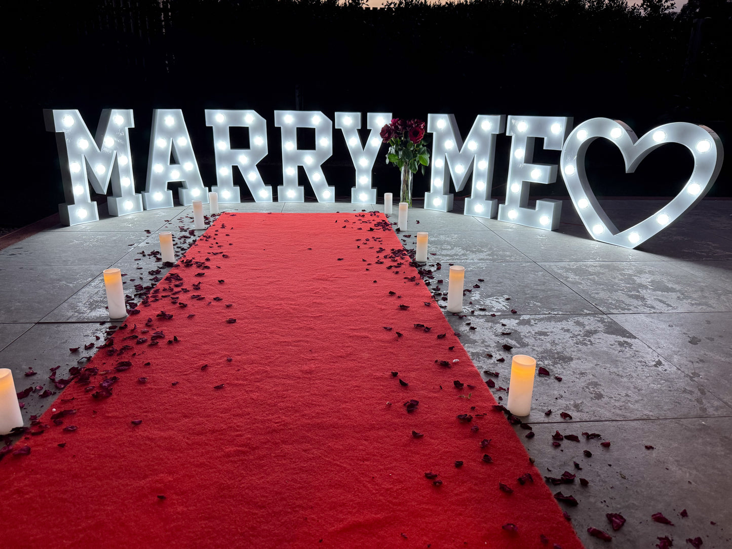 Red carpet hire Melbourne with marry me marquee letters, heart light, candles and rose petals
