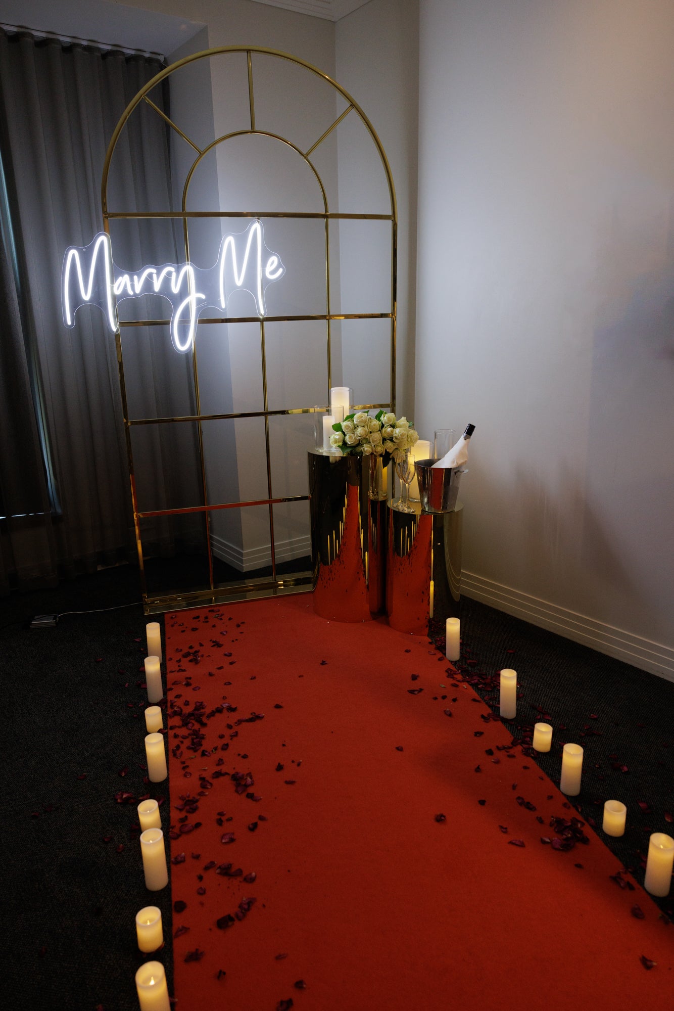 Red carpet hire Melbourne with marry me neon sign, gold backdrop, candles and roses