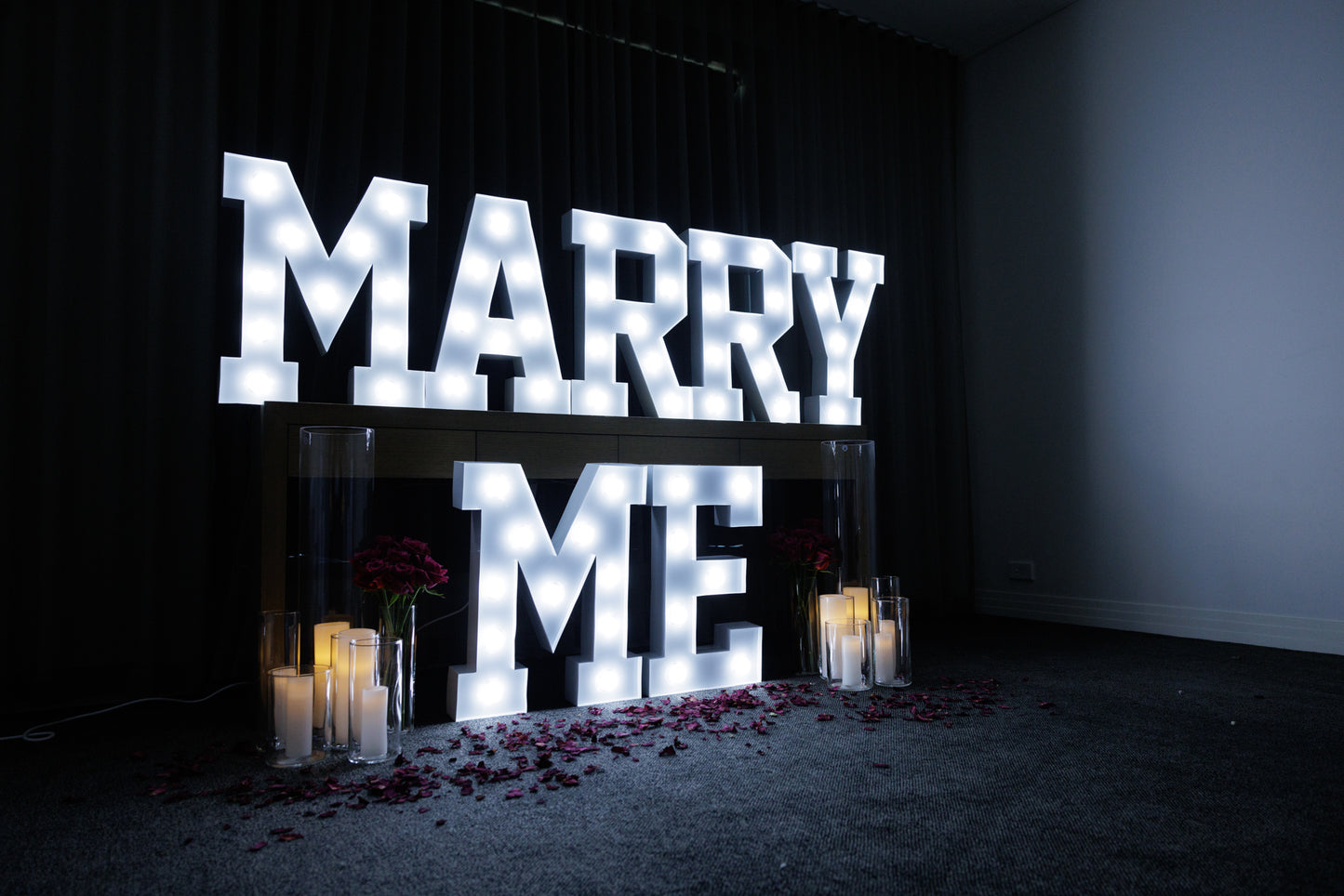 Marry me light-up letters with candles and rose petals for romantic proposal setting