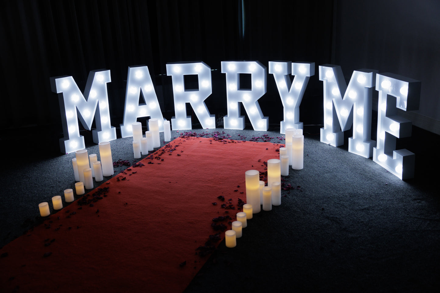 Red carpet hire Melbourne with marry me marquee lights and candles for proposal