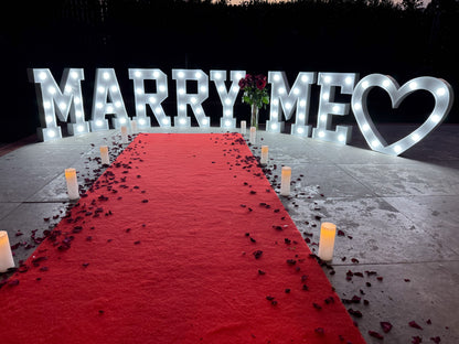 Red carpet hire Melbourne with marry me marquee letters, heart light, candles and rose petals