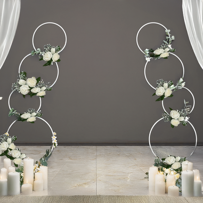 Two white round hoop backdrop stands with multiple circular hoops, decorated in white roses and babies breath flowers.